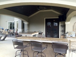 This covered patio features a wet bar, kegerator, grill and mounted TV. The roof extension matches the exterior of the home. too. This outdoor living space was designed by Outdoor Homescapes of Houston in Cypress, TX. For more ideas and inspiration, visit www.outdoorhomescapes.com