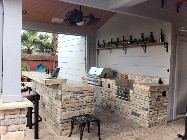 With its rustic shelf decorations, ceiling fan and natural stone island, this outdoor kitchen is one of the outdoor living spaces perfect for celebrating Go Texan Day 2014. For other outdoor living designs and ideas by Outdoor Homescapes of Houston, visit www.outdoorhomescapes.com.