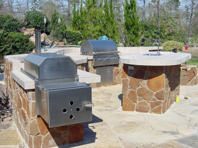 This outdoor kitchen by Outdoor Homescapes of Texas is one of the outdoor living spaces featured by the outdoor design company for Go Texan Day 2014. It features a professional grade smoker built into a natural stone island. The outdoor living space also has a sink and a grill. For more outdoor living designs like this, visit www.outdoorhomescapes.com