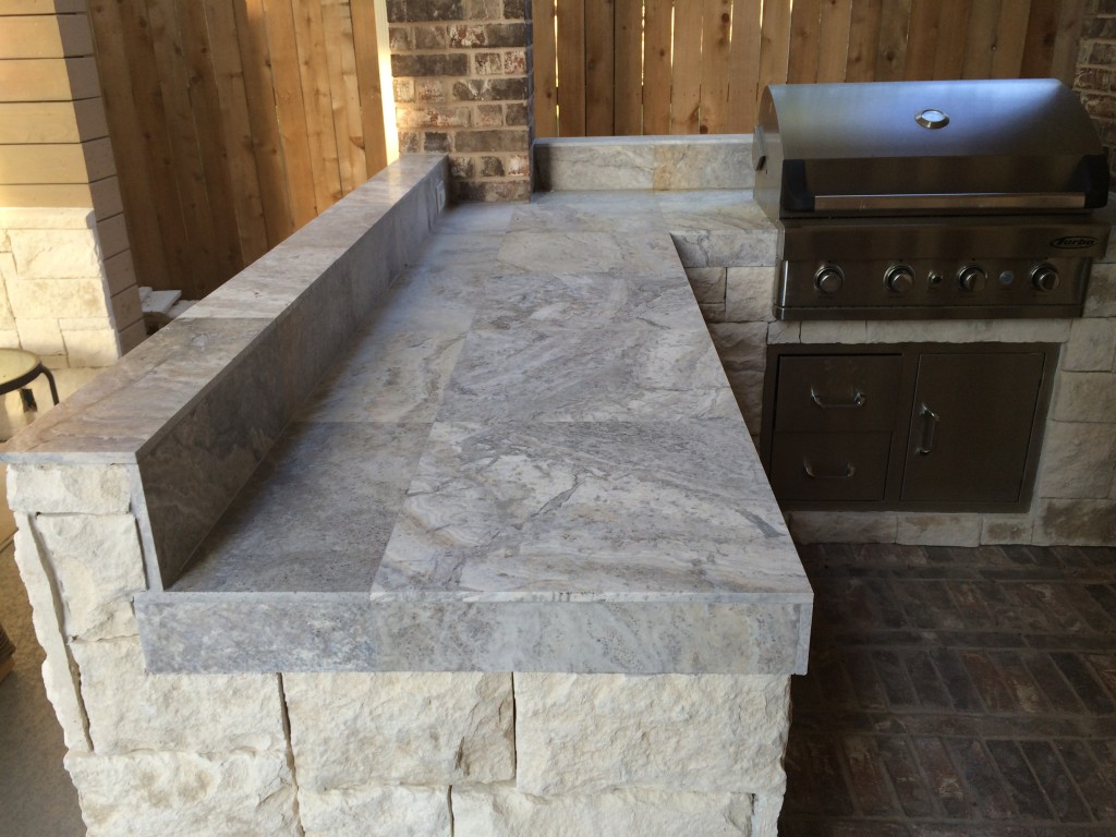 Silver travertine tile can be a unique, stylish countertop, as seen in this outdoor kitchen by Outdoor Homescapes of Houston. more at www.outdoorhomescapes.com.