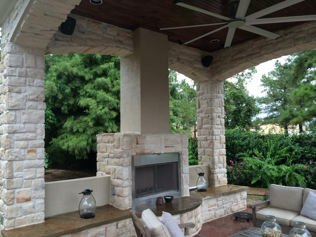 This Houston outdoor sitting area contains a gas fireplace with bench seating, an outdoor ceiling fan, outdoor sofas and a coffee table. This is one of the many Houston patio covers designed and built by Outdoor Homescapes of Houston. More at www.outdoorhomescapes.com.