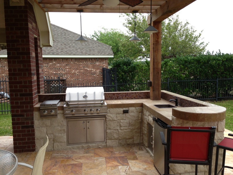 This Houston patio addition features a double pergola and outdoor kitchen with a curved raised bar and travertine tile. More at www.outdoorhomescapes.com/blog